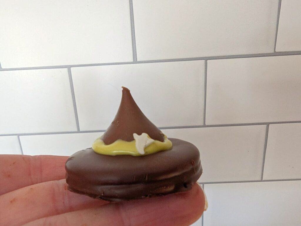 Image shows a Hand holding witch hat oreo cookie.