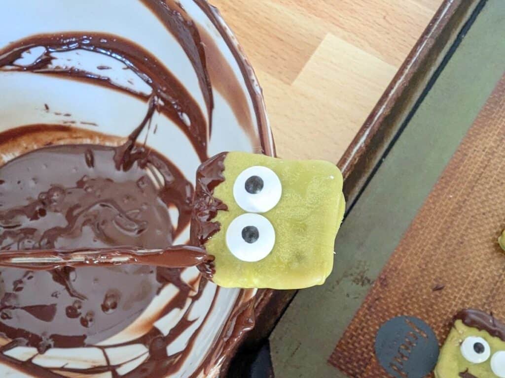 Image shows Using a chocolate spear tool to make chocolate hair on a pretzel.