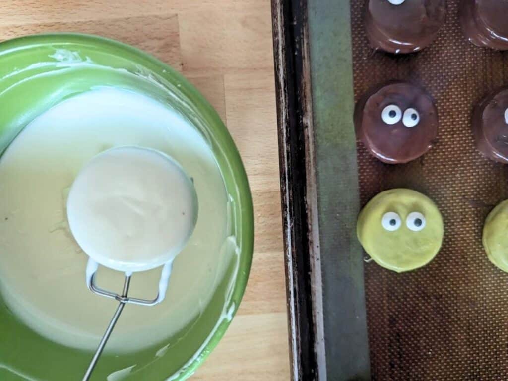 Image shows White chocolate dipped oreo being removed from chocolate.