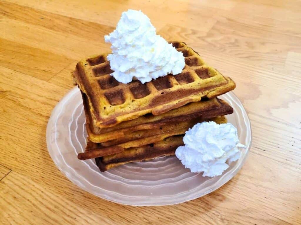 Image shows yummy pumpkin waffles with whipped cream.