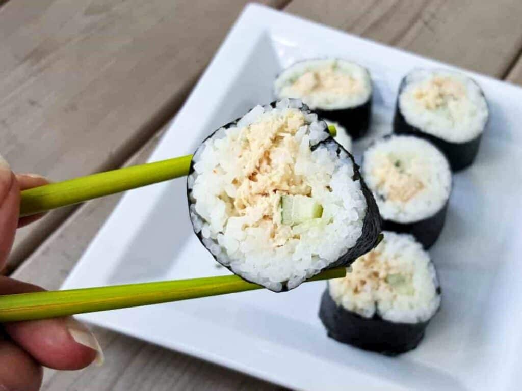 Image shows yummy spicy tuna roll in a chopstick.