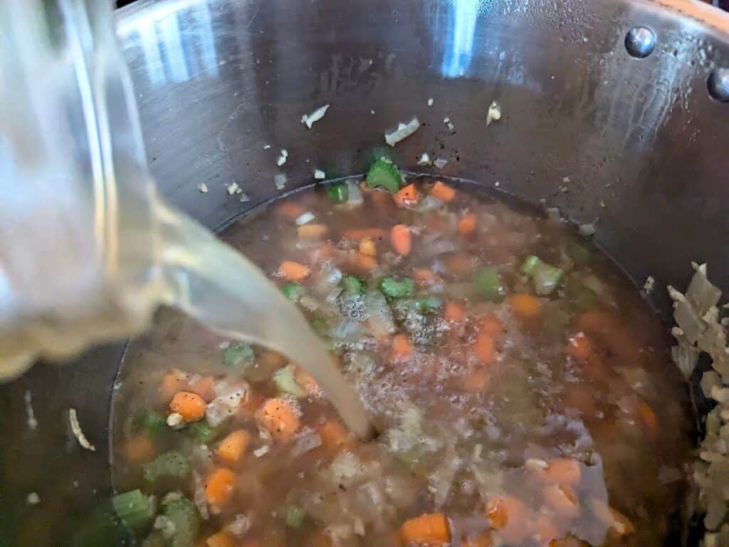 Image shows chicken stock added into the Instant Pot with vegetables.