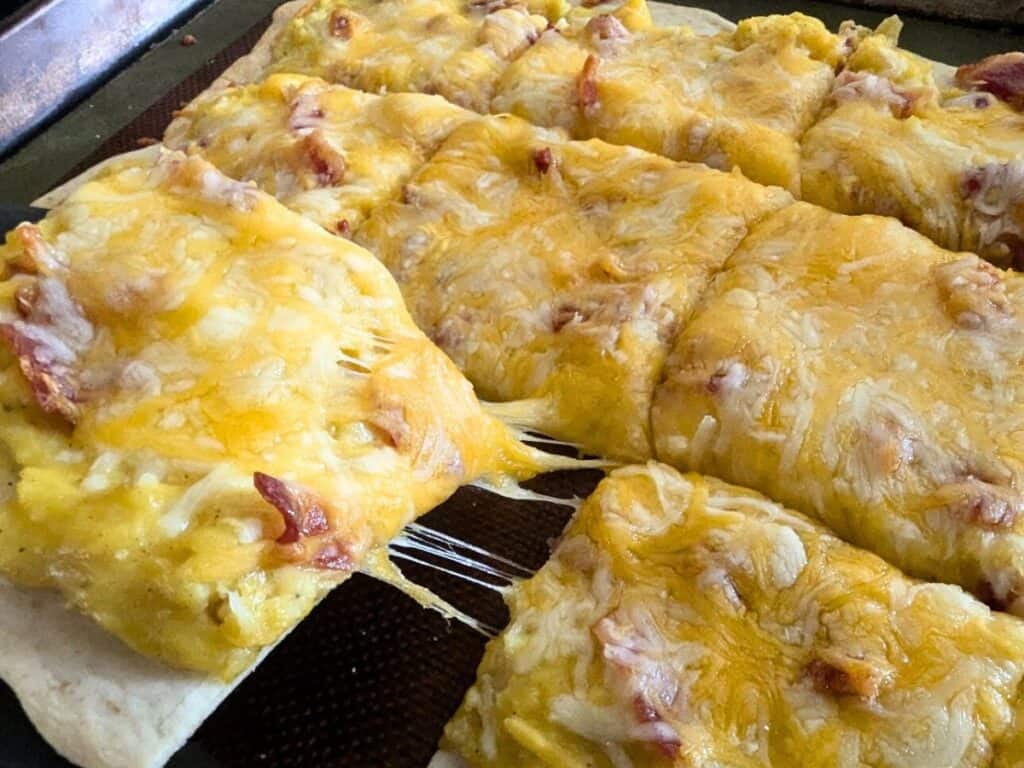 Image shows close-up of easy to make breakfast pizza cut in squares.