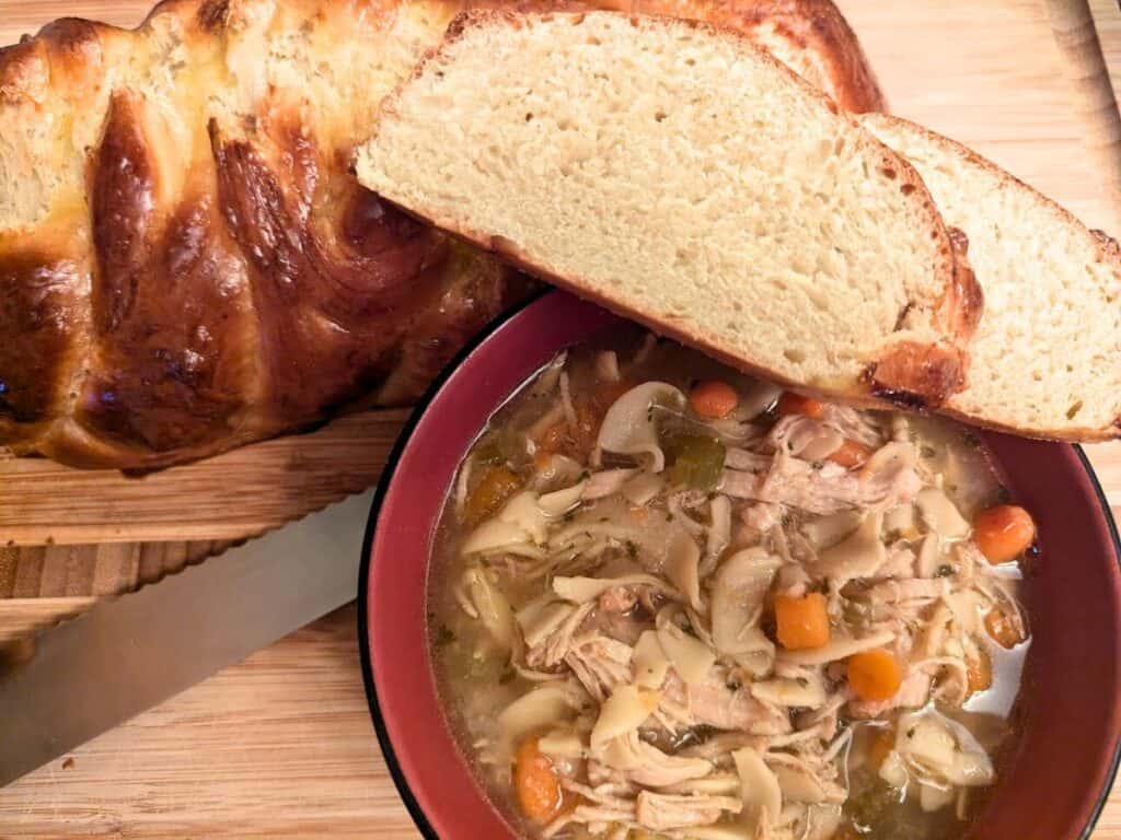Image shows Instant Pot chicken noodle soup with challah.