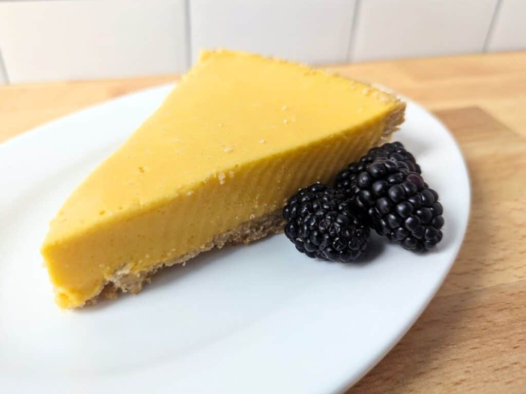 Image shows slice of mango pie on a plate with fruit.