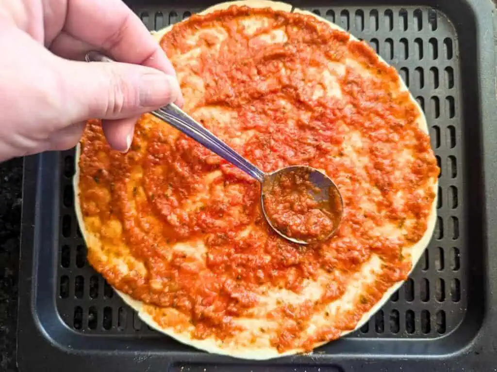 Image shows putting tomato sauce on the tortilla.