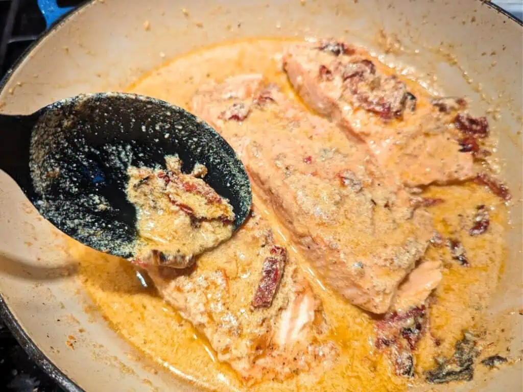 Image shows add the salmon fillets to the pan with the sauce.