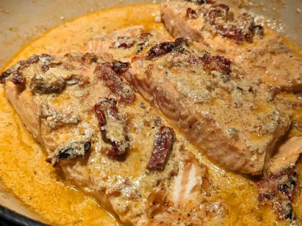 Image shows cooked and ready to serve creamy sun-dried tomato salmon.