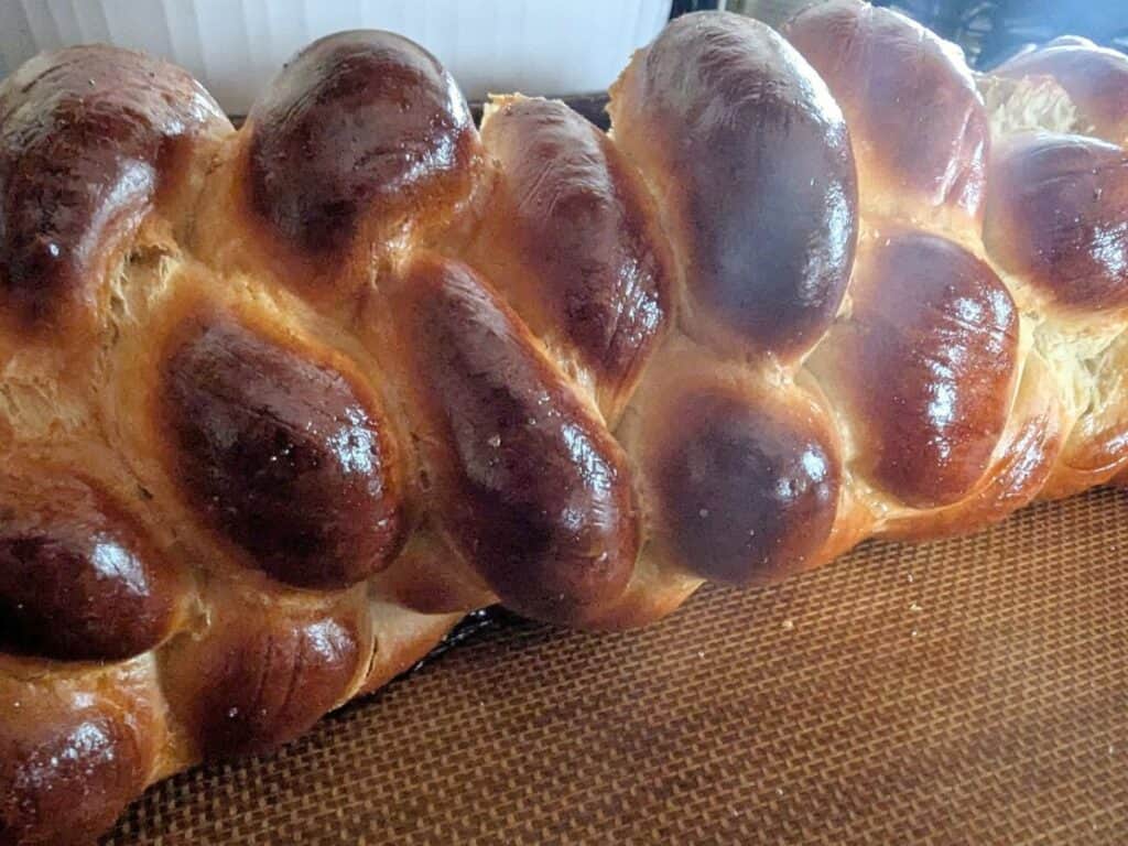 Image shows delicious and freshly baked challah bread on a Silpat-lined baking sheet.
