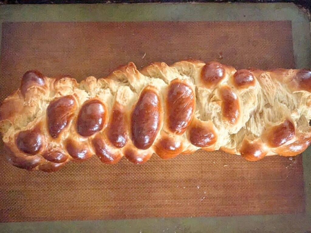 Image shows freshly baked challah bread on a Silpat-lined baking sheet.