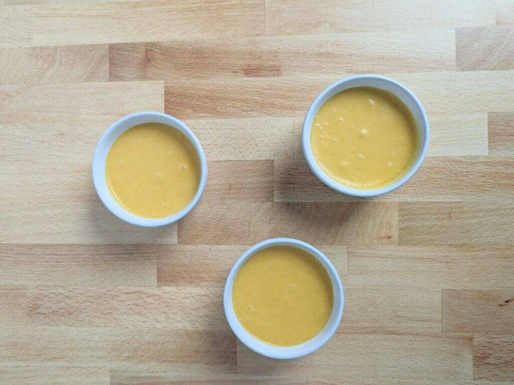 Image shows three ramekins of mango mousse ready to be chilled.