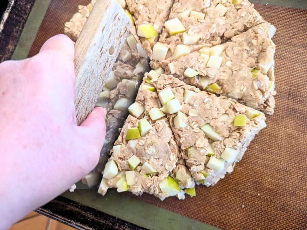 Image shows Apple scone dough being cut into eight pieces with a bench scraper.