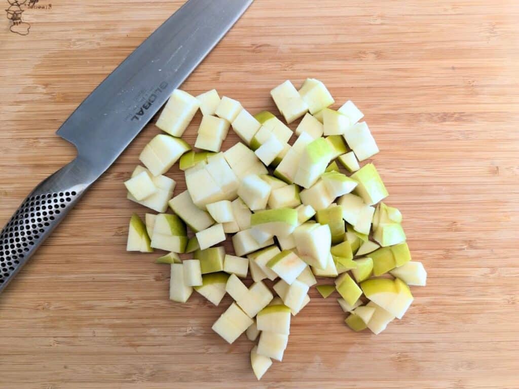 Image shows Freshly chopped apples on a cutting board for apple scones.