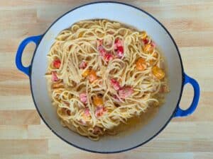 Image shows A pan filled with hot, cooked bigoli with grape tomatoes and ricotta ready to be served.