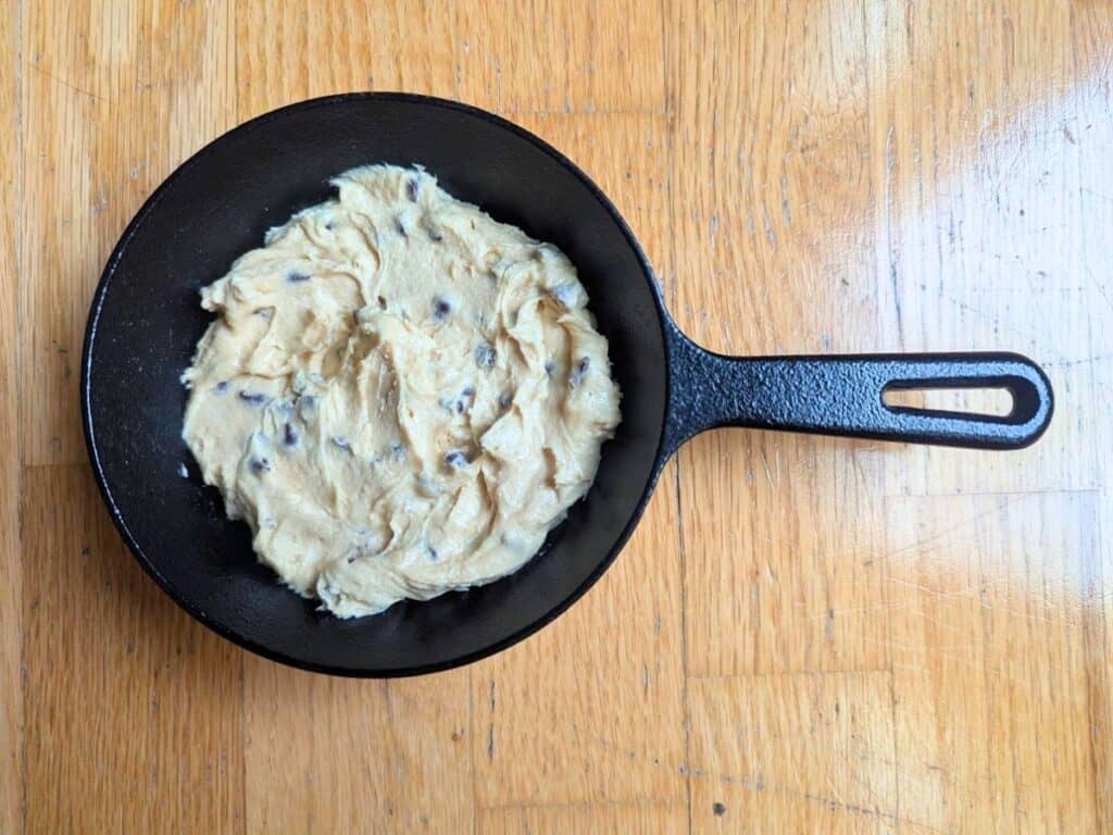Image shows batter for individual chocolate chip skillet cookie placed in a mini skillet.