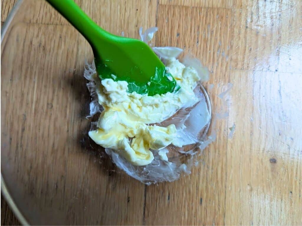 Image shows close-up of softened butter in a bowl with a spatula.