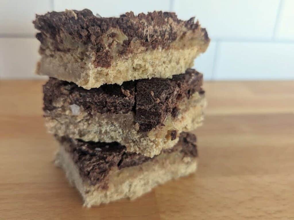 Image shows baked homemade cookie bar on a wooden counter.