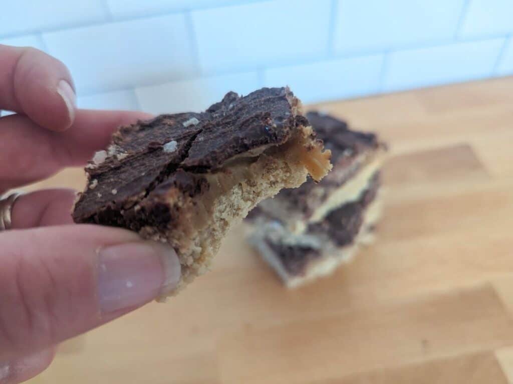 Image shows close-up of a hand holding a partially eaten cookie bar.