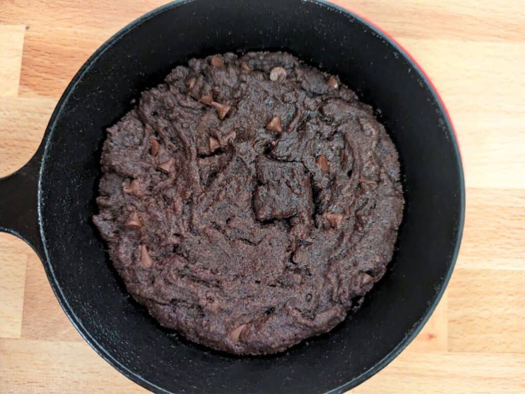 Image shows close-up of freshly baked brownie cookie in a cast iron skillet.