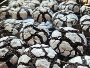 Close-up of chocolate crinkle cookies with powdered sugar on top, arranged on a cooling rack.