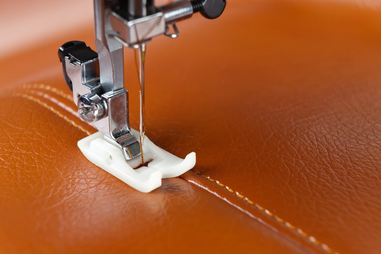 Close-up of a sewing machine stitching durable vinyl material with reinforced seams for high-quality hot tub covers.