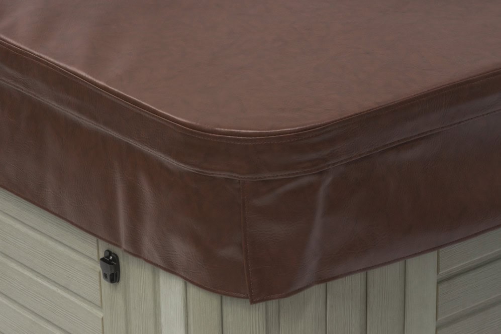 Close-up view of a brown vinyl hot tub cover secured over a light wood-paneled hot tub.