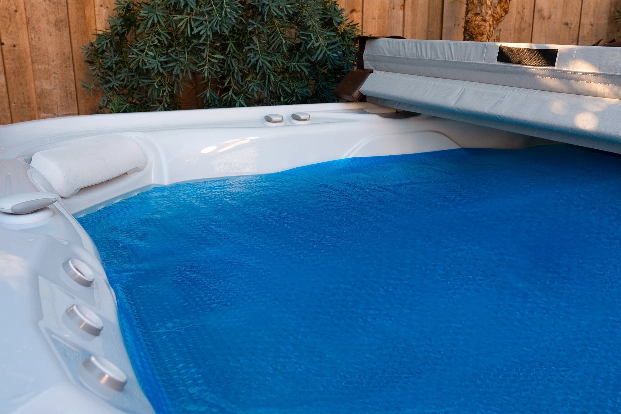 Hot tub solar blanket floating on water inside a hot tub, providing insulation and energy efficiency