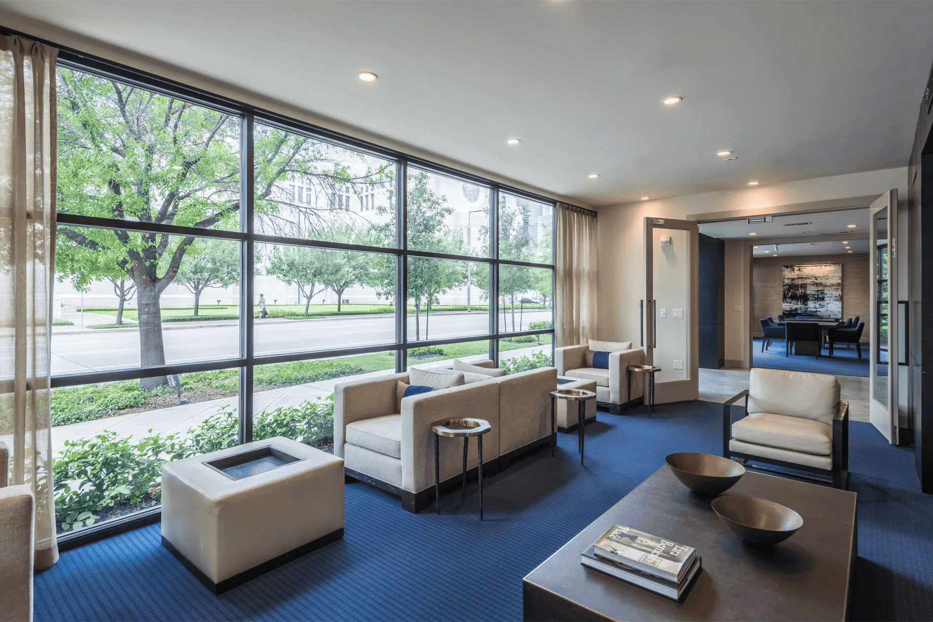 Modern interior lounge space with large windows overlooking trees, comfortable seating, and contemporary decor, ideal for EB5 investors exploring Houston real estate opportunities.