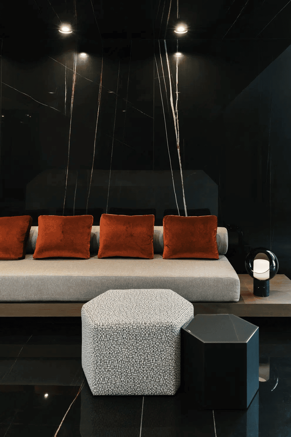 Luxury modern living room interior with gray sofa, orange cushions, black marble walls, and unique lighting, suitable for upscale Houston EB5 investment properties.