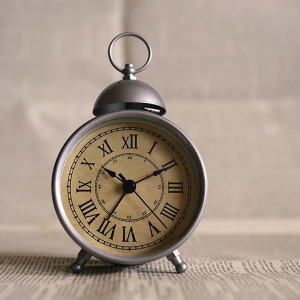 Alarm clock with vintage design, showing time at 10:09, placed on a newspaper background, symbolizing time sensitivity in Houston EB5 investment opportunities.