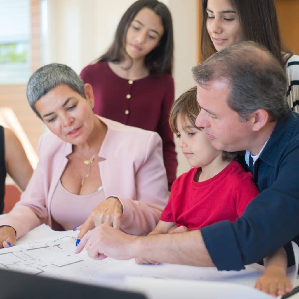 Diverse group of adults and children collaborating on Houston EB-5 investment project, discussing business plans and immigration opportunities.