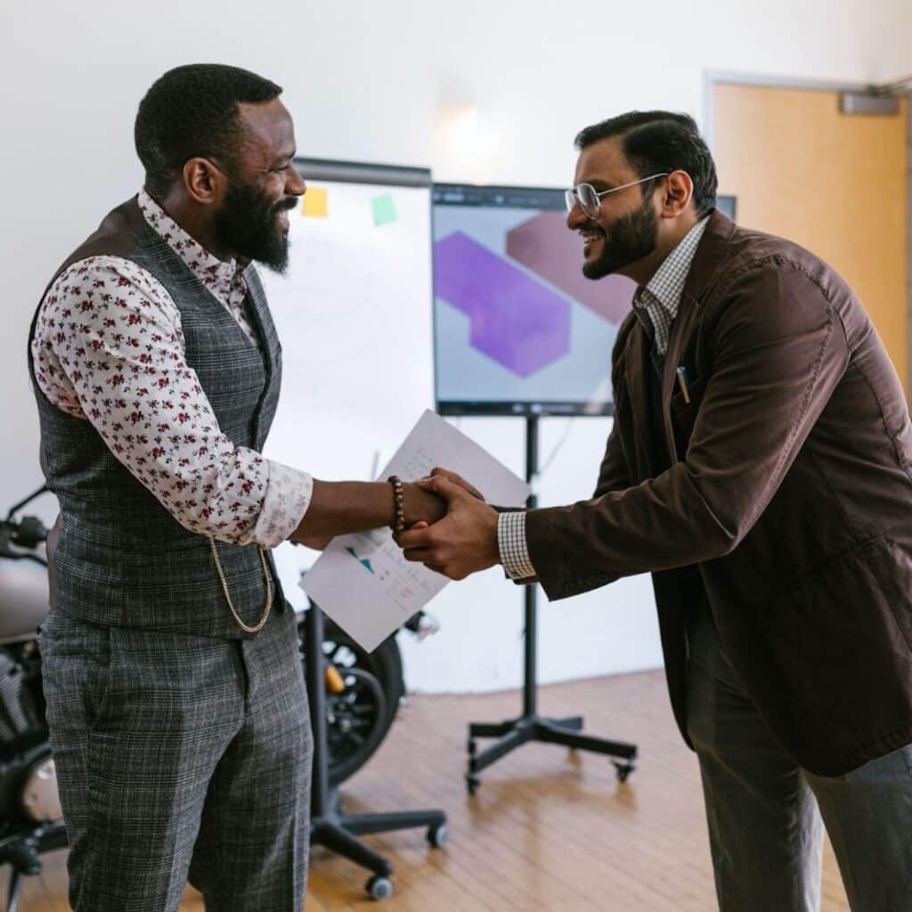 Professional business handshake between diverse men promoting Houston EB5 investment opportunities in a modern office.
