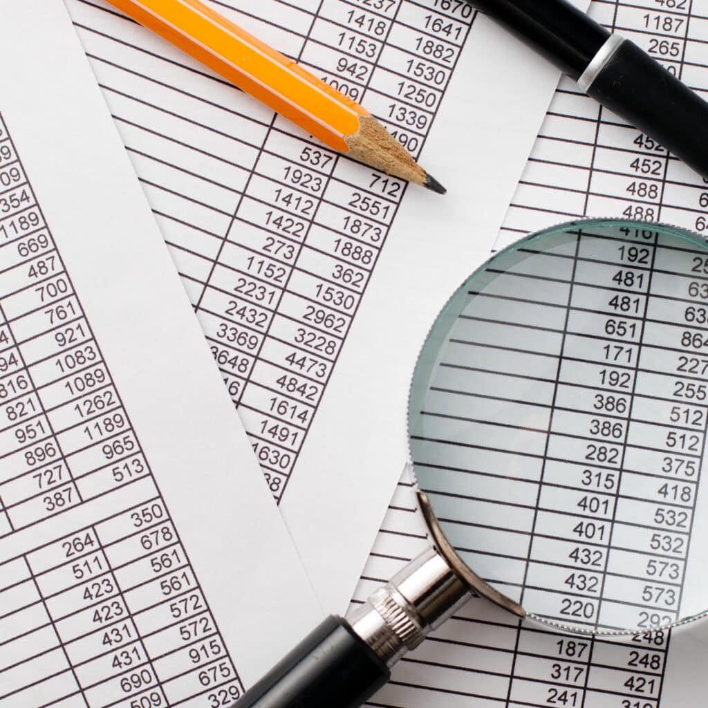 Banking financial data sheets with magnifying glass, pen, and pencil, representing Houston EB5 investment opportunities, immigration, and visa process analytics.