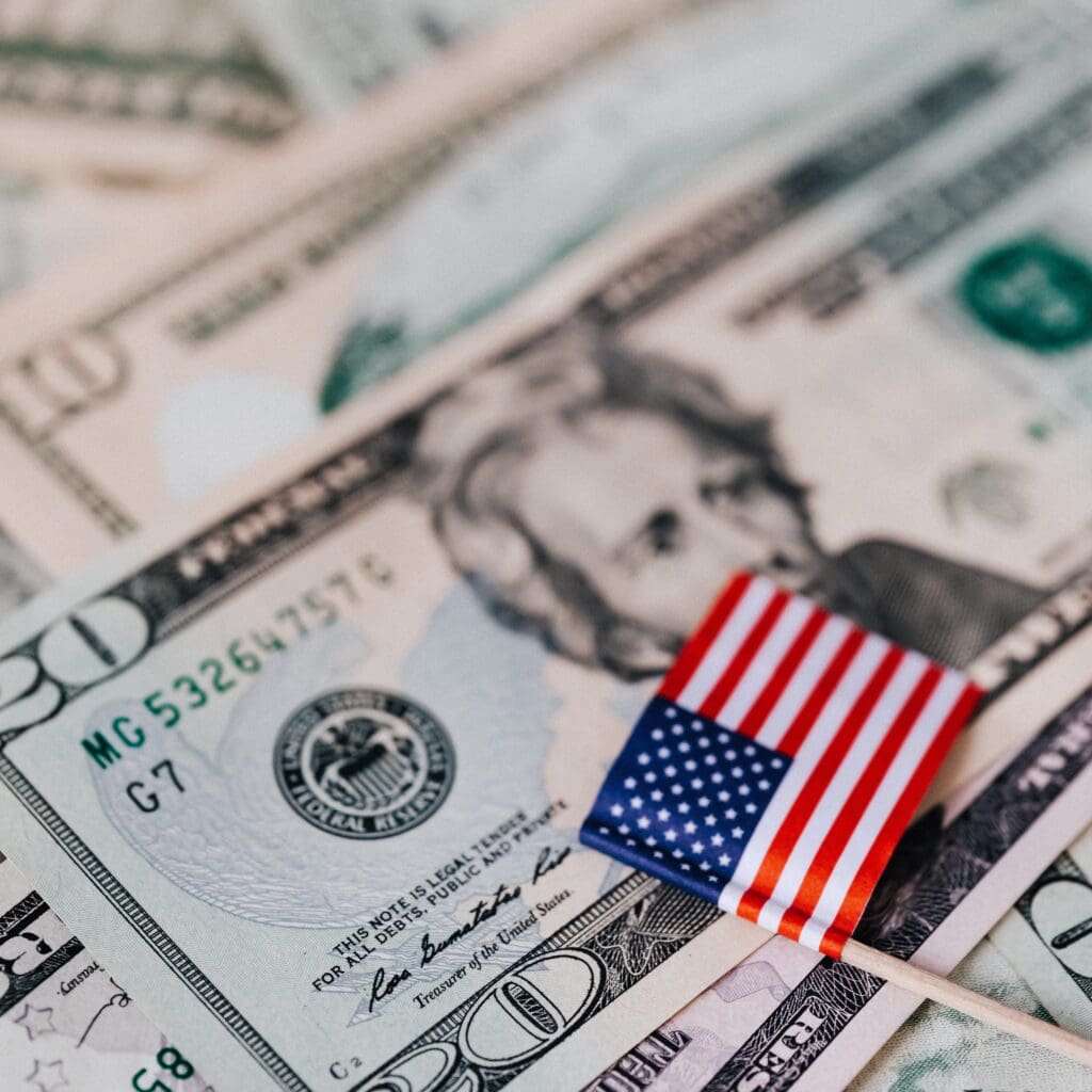 $100 bills with small American flag, emphasizing investment opportunities in Houston EB5 programs for U.S. immigration and business growth.