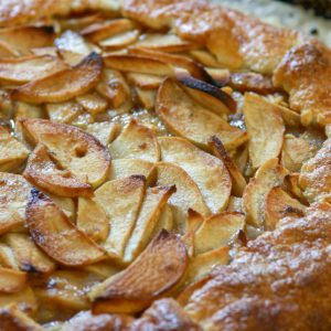 Close up image of apple galette on a parchment lined baking sheet.