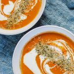 two bowls of tomato coconut soup.