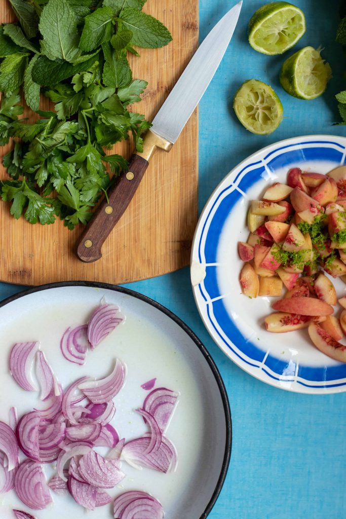 prepared peach quinoa salad ingredients on a blue table.