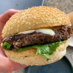 someone holding a mushroom walnut burger over a plate.