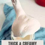 An immersion blender covered in freshly made mayonnaise with a jar of mayonnaise, a blue napkin, and a red pot in the background. Text on the image says "thick & creamy mason jar mayo."