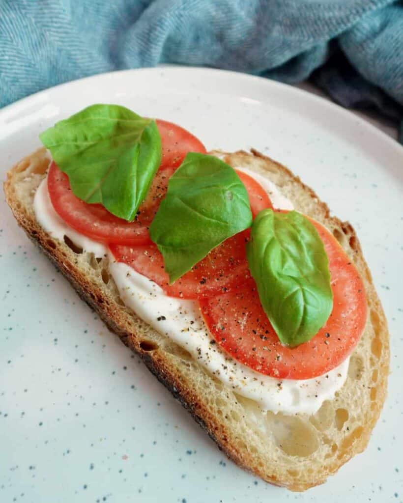 Vegan mayo on sourdough bread with tomatoes and basil.