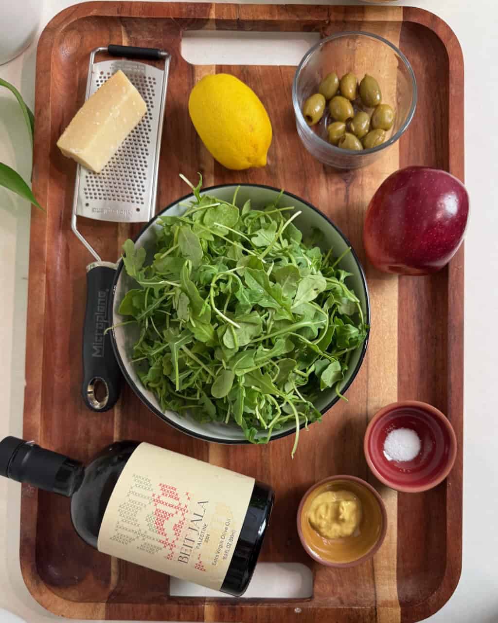 Arugula salad ingredients arranged on a wooden board.