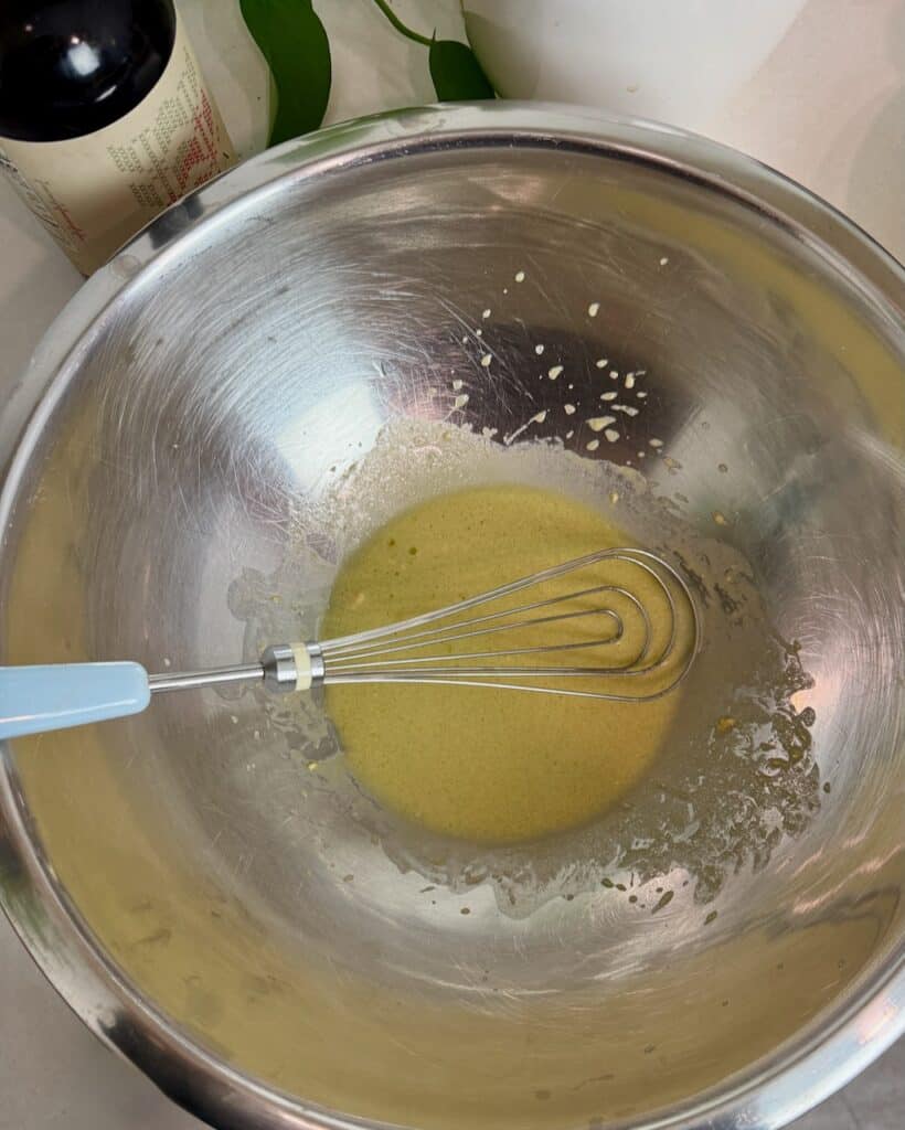 The finished salad dressing in a stainless steel bowl with a whisk.
