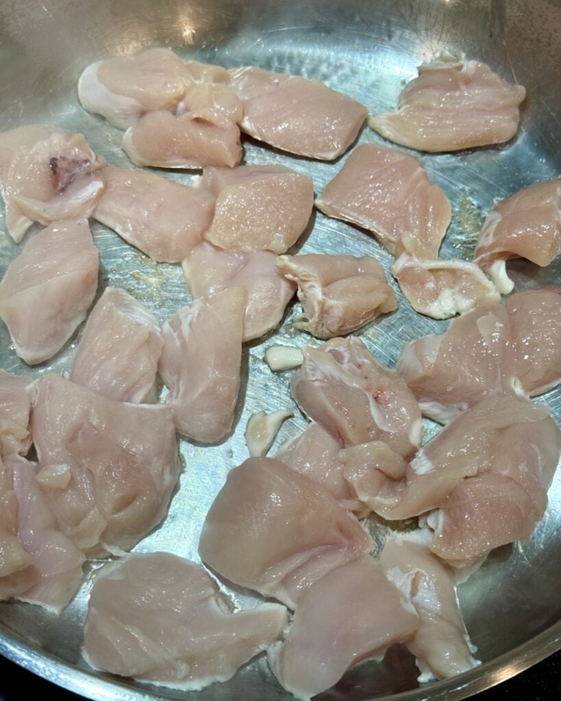 Spreading the chicken cubes in a single layer in the pan.