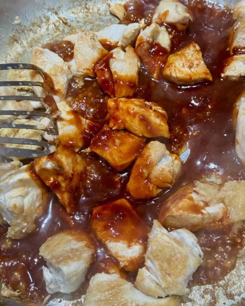 Adding the sauce to the chicken and stirring.