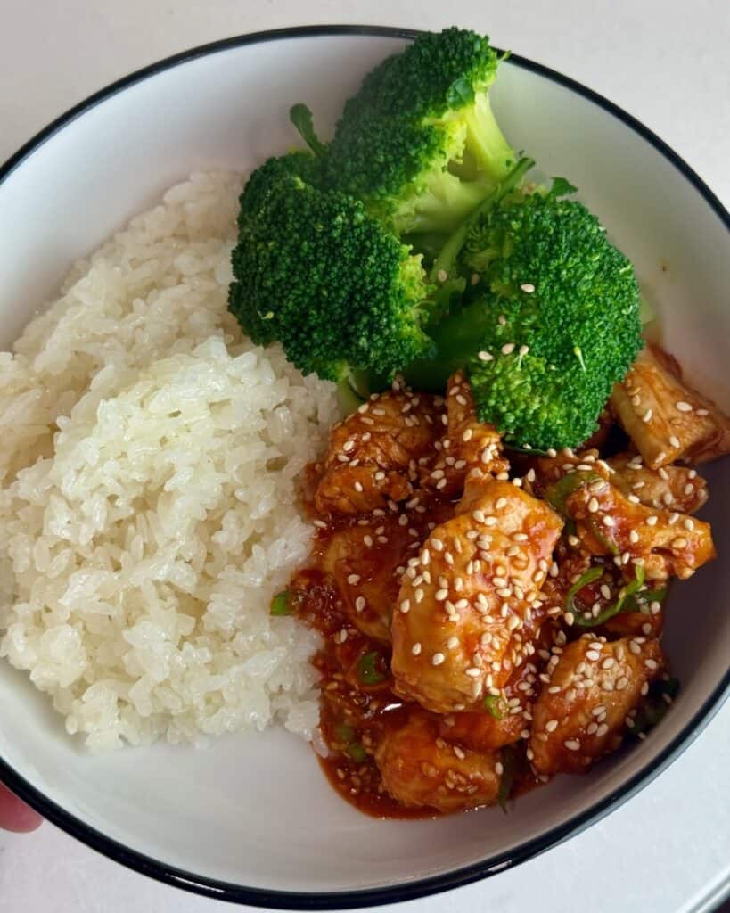 Gochujang chicken, steamed broccoli and rice in a white bowl.