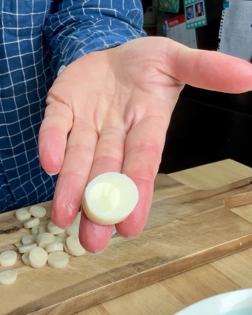 A woman holding a slice of hearts of palm.
