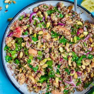 a bowl of peach quinoa salad on a blue table.