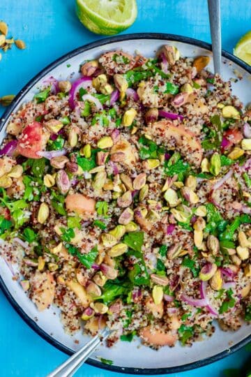 a bowl of peach quinoa salad on a blue table.