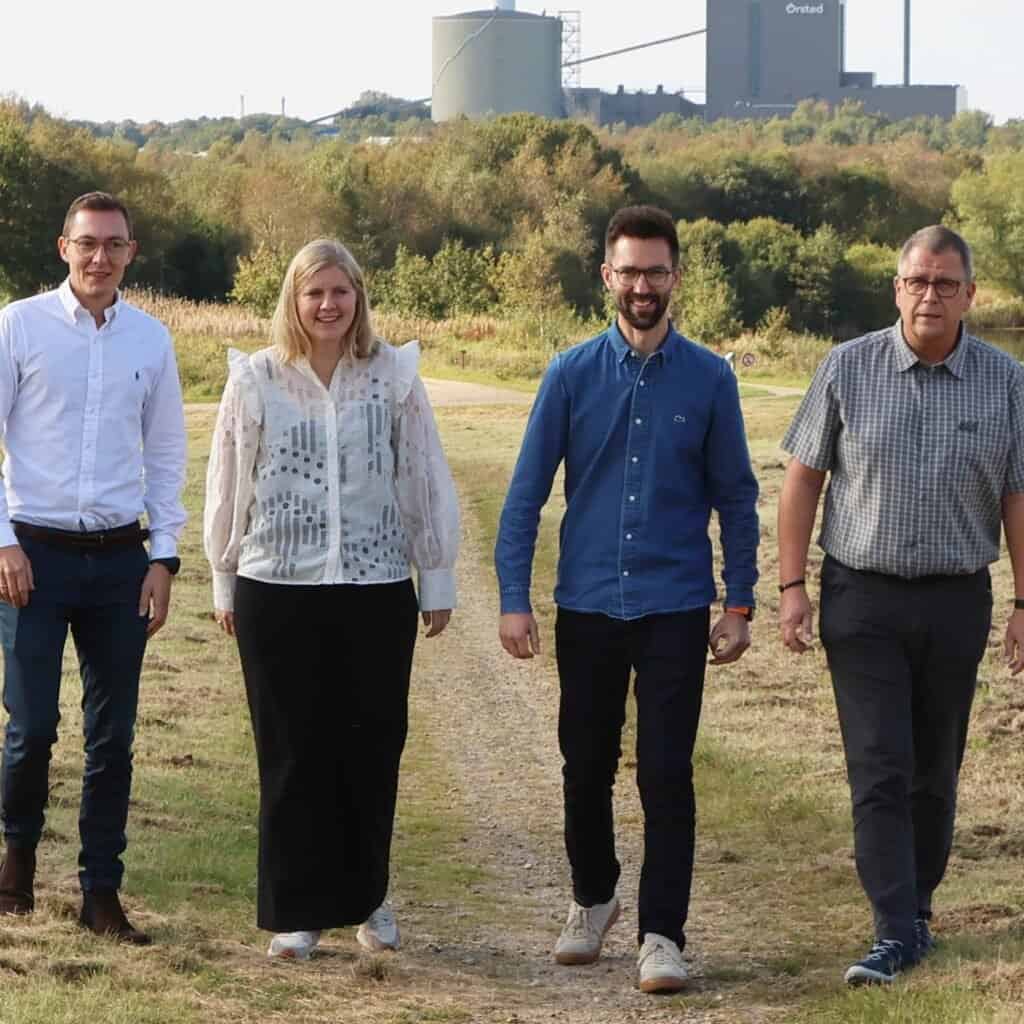 Mennesker gående udendørs i natur, repræsenterer teamwork og professionalisme.
