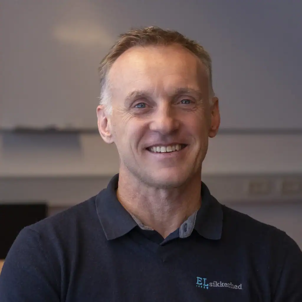 Text alt: Smilende mand i sort sweater med logo, professionel portræt.